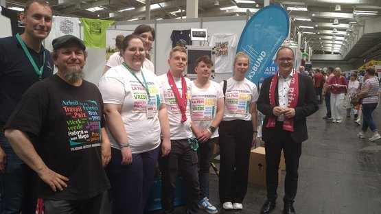 Eine Gruppe von Frauen und Männern vor dem Volksbundstand. Im Hintergrund eine blaue Beachflag des Volksbundes.