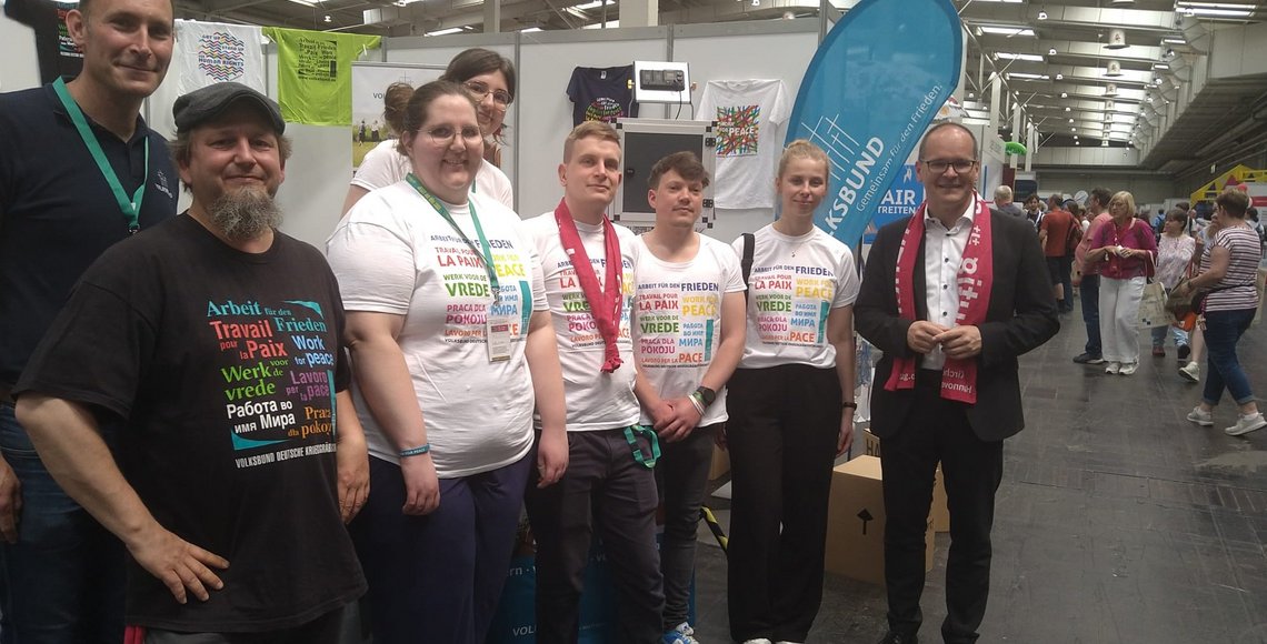 Eine Gruppe von Frauen und Männern vor dem Volksbundstand. Im Hintergrund eine blaue Beachflag des Volksbundes.