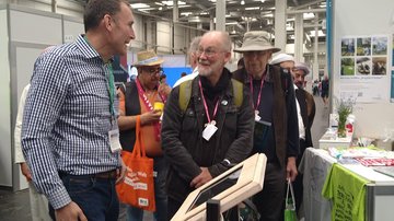 Besucher unterhalten sich am Stand mit einem Mitarbeiter. Sie lachen