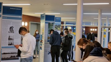 Schülerinnen und Schüler vor der Ausstellung „Zeitenwende ’45 – Aufbruch in ein neues Europa“. Sie arbeiten mit Tablets und tragen Masken.